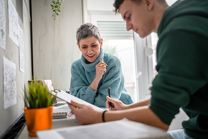 Woman tutor helping young college aged man